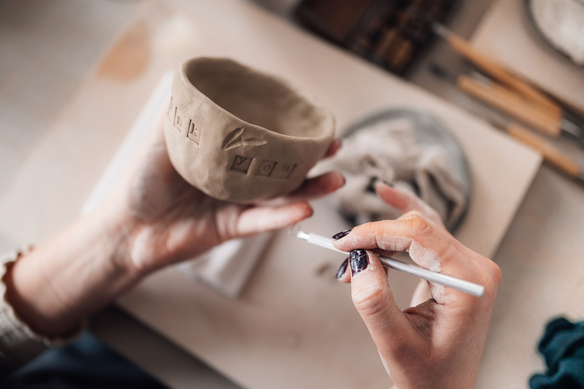Close up of pottery artisan's hands decorating earthenware at studio.